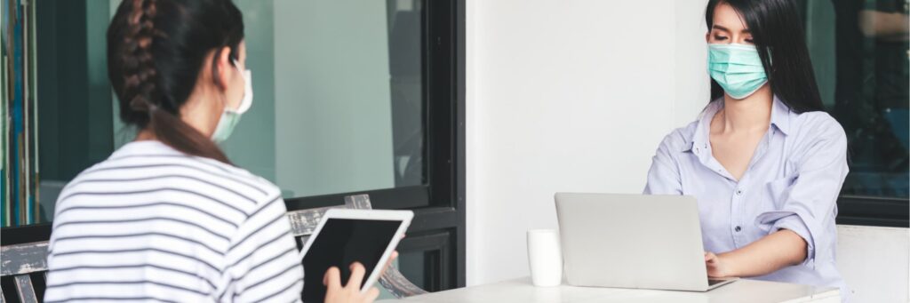 Coworkers working together but socially distanced with masks