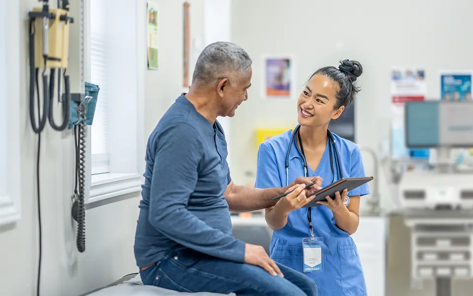 A doctor and patient smiling while talking during an office visit.